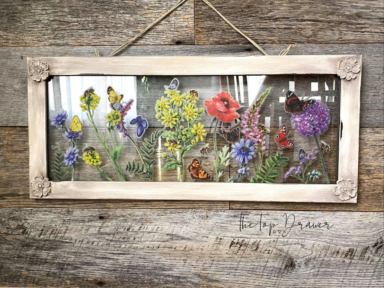 WoodUBend Floral Applique #1479 (Set of 5) is the perfect mouldable embellishment for any project!
A framed clear plastic with the Wildflowers & Butterflies - Transfer, on all 4 corner of the frame is the Floral Applique #1479 . Staged hanging on a rustic wood wall.
