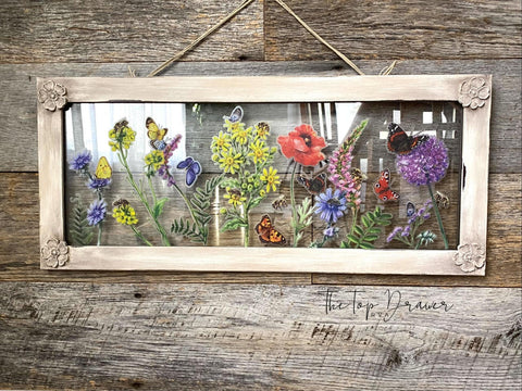WoodUBend Floral Applique #1479 (Set of 5) is the perfect mouldable embellishment for any project!
A framed clear plastic with the Wildflowers & Butterflies - Transfer, on all 4 corner of the frame is the Floral Applique #1479 . Staged hanging on a rustic wood wall.