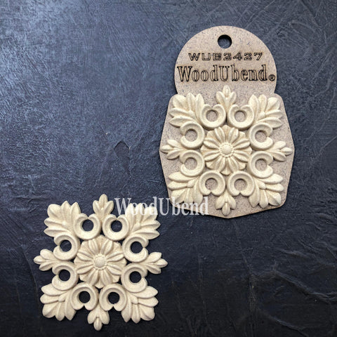 WoodUBend Floral Applique #2427 (set of 2) is the perfect mouldable embellishment for any project!
Image shows 2 of the Floral Applique #2427, one in the packaging and the other out of the packaging. Staged on top of a black background.