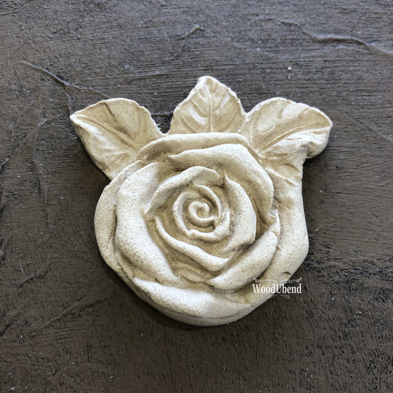 WoodUBend Floral Applique #465 (set of 5) is the perfect moldable embellishment for any project!
A close up of the Floral Applique #465 that comes in a Set of 5. The applique looks like a rose with leaves on the back, staged on a black background.