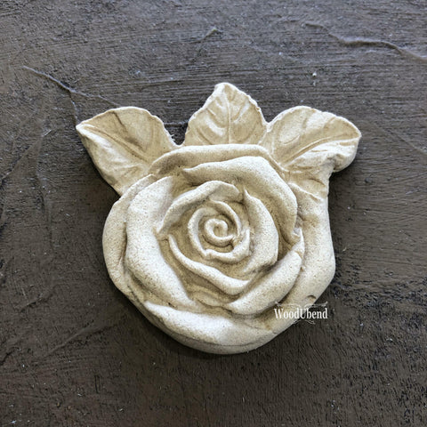 WoodUBend Floral Applique #465 (set of 5) is the perfect moldable embellishment for any project!
A close up of the Floral Applique #465 that comes in a Set of 5. The applique looks like a rose with leaves on the back, staged on a black background.