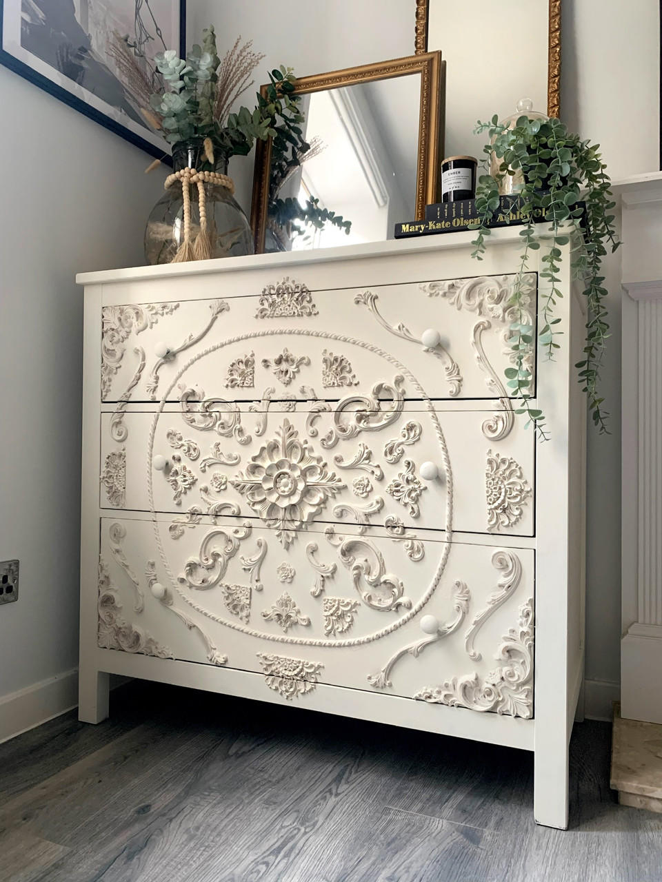 WoodUBend Ring Applique #1520 (set of 2) is the perfect mouldable embellishment for any project! A white dresser with 3 long drawers, featuring various different wooden appliques in various different sizes. This dresser is staged with 2 mirrors and different household decor.