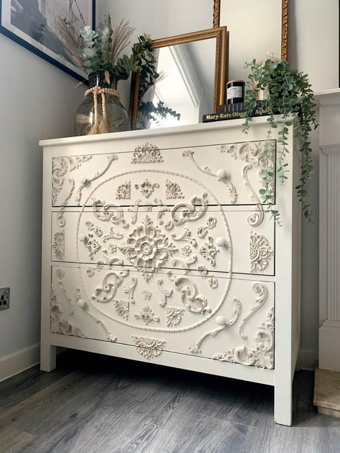 WoodUBend Ring Applique #1520 (set of 2) is the perfect mouldable embellishment for any project! A white dresser with 3 long drawers, featuring various different wooden appliques in various different sizes. This dresser is staged with 2 mirrors and different household decor.