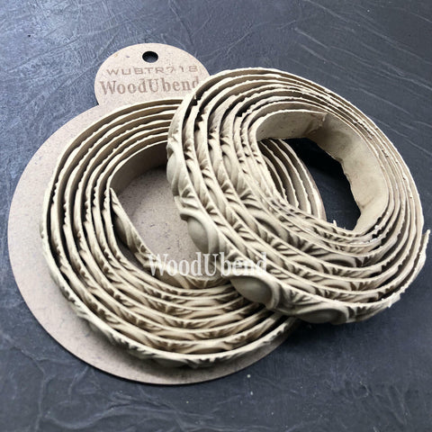 WoodUBend Trim #TR718 (Set of 2) is the perfect mouldable embellishment for any project!  Two rolls of WoodUbend sitting on top of a brown round cardboard cutout with WoodUbend WUBTR718 printed at the top; all sitting on a black table.
