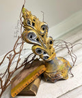 Fleur- de-lis type statue sprayed with Yellow Patina Spray. Staged with stacked books and a branch.