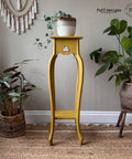 Yellow painted plant stand table makeover with a white, silver, and bronze pot containing a faux Pothos on top.